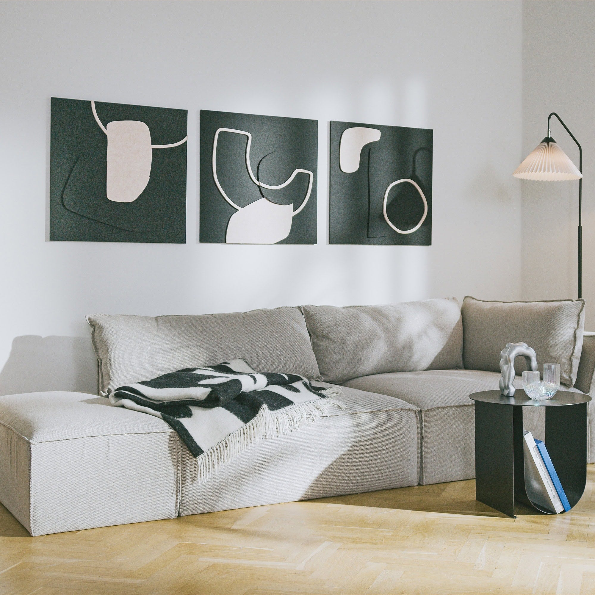 Decorative acoustic sound panels with abstract design mounted above light grey sofa in modern living room